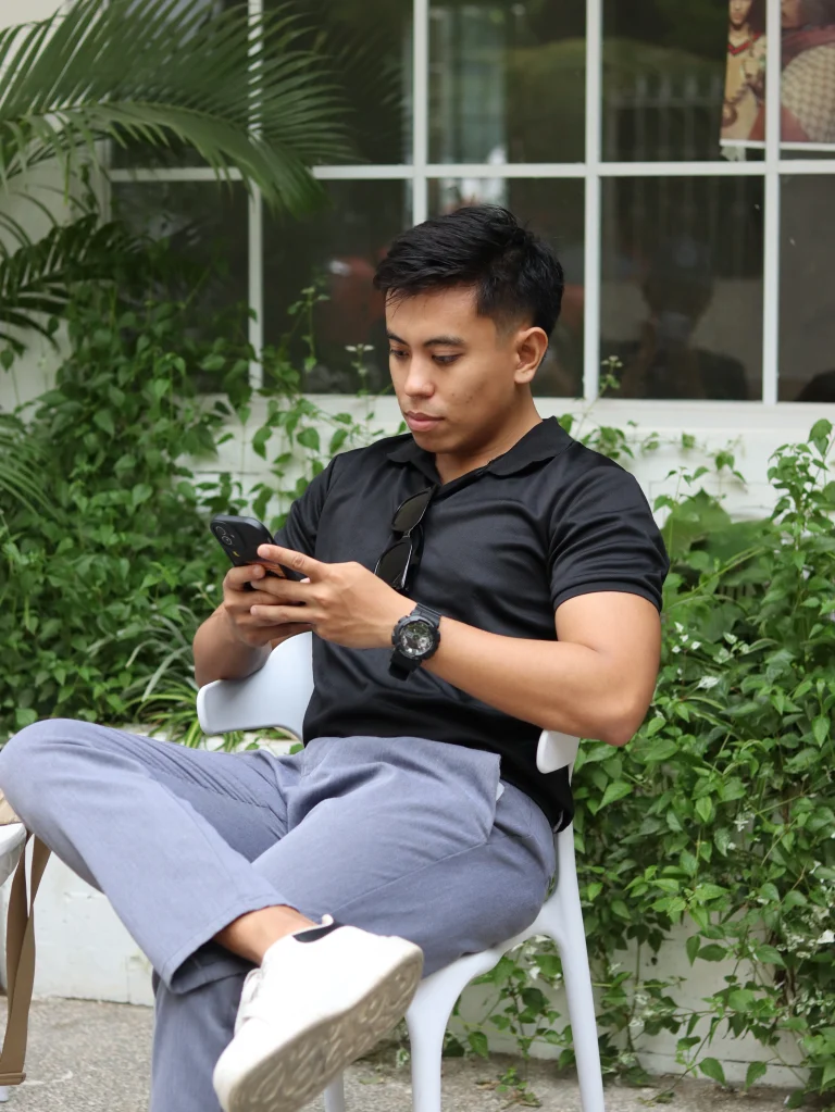 Man using his phone while sat down on a chair